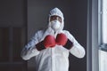 Doctor in hazmat suit posing with boxing gloves