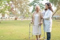 Doctor help and care Asian senior or elderly old lady woman use walker with strong health while walking at park in happy fresh Royalty Free Stock Photo