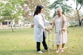 Doctor help and care Asian senior or elderly old lady woman use walker with strong health while walking at park in happy fresh Royalty Free Stock Photo