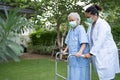 Doctor help and care Asian senior or elderly old lady woman use walker with strong health while walking at park in happy fresh Royalty Free Stock Photo