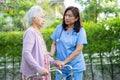 Doctor help and care Asian senior or elderly old lady woman use walker with strong health while walking at park in happy fresh Royalty Free Stock Photo