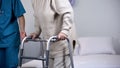 Doctor helping elderly female with walking frame, health care, hospital recovery