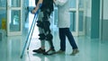 Doctor is helping a patient to walk while wearing exosuit