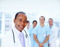 Doctor with his staff. Focus on doctor with team in background. Royalty Free Stock Photo