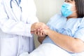 doctor hold hands patient Which wearing a surgical mask and lying in the patient`s bed, to encourage