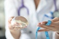 Doctor holding breast implant and measuring tape closeup Royalty Free Stock Photo