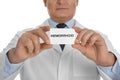 Doctor holding business card with word HEMORRHOID on background, closeup