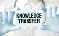 Doctor holding card in hands and pointing the word KNOWLEDGE TRANSFER