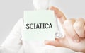 Doctor holding card in hands and pointing the word SCIATICA