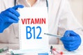 Doctor holding card in hands and pointing the word VITAMIN B12. Medical concept