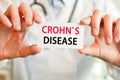 Doctor holding a card with text CROHNS DISEASE in hands. Medical concept