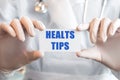 Doctor holding a card with text HEALTS TIPS