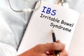 Doctor holding a card with text IBS, medical concept