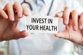 Doctor holding a card with text INVEST IN YOUR HEALTH Royalty Free Stock Photo