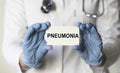 Doctor holding a card with text word PNEUMONIA, medical concept