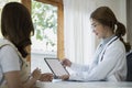 Doctor holding digital tablet and explaining diagnosis to her female patient. Royalty Free Stock Photo