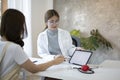 Doctor holding digital tablet and showing positive test results to her patient at hospital. Royalty Free Stock Photo