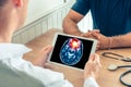 Doctor holding a digital tablet with x-ray of brain of the patient. Brain cancer or headache prevention Royalty Free Stock Photo