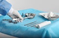 Doctor holding forceps over table with surgical instruments against light background, closeup Royalty Free Stock Photo