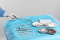 Doctor holding forceps over table with surgical instruments against light background, closeup Royalty Free Stock Photo