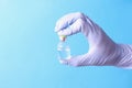 Doctor holding glass ampoule with medicine in rubber gloves closeup