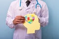 Doctor holding head with jigsaw puzzle brain shape - Autism spectrum disorder concept