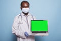 Doctor holding laptop with green screen