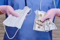 Doctor holding a medical mask and money. Nurse with dollars in hands and protective medical gloves, close-up