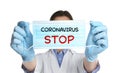 Doctor holding medical mask with text Coronavirus Stop on background. Protective measures during pandemic