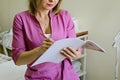 Doctor holding a notebook in his hand. Close up of female beautician in pink uniform filling out a medical form