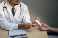 Doctor Holding pack of tablet blisters in hand in front of patient and reviewing his medication