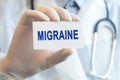 Doctor holding a paper card with text MIGRAINE, medical concept Royalty Free Stock Photo