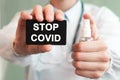 Doctor holding a paper card with text STOP COVID and the medicine bottle, medical concept Royalty Free Stock Photo