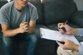 Doctor holding pen is checking the patient condition and is explaining the results of the examination to the patient listening at