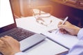 Doctor holding pen writing report Cancer Treatment Plan on desk with sunset light. Royalty Free Stock Photo