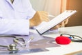 Doctor holding pen writing report Cancer Treatment Plan on desk with sunset light Royalty Free Stock Photo