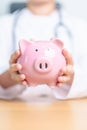 Doctor holding piggy bank and putting coin. and Healthcare cost, Money Saving, Health Insurance, Medical, Donation and Financial Royalty Free Stock Photo