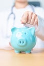 Doctor holding piggy bank and putting coin. and Healthcare cost, Money Saving, Health Insurance, Medical, Donation and Financial Royalty Free Stock Photo