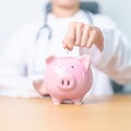 Doctor holding piggy bank and putting coin. and Healthcare cost, Money Saving, Health Insurance, Medical, Donation and Financial Royalty Free Stock Photo