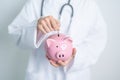 Doctor holding piggy bank and putting coin. and Healthcare cost, Money Saving, Health Insurance, Medical, Donation and Financial Royalty Free Stock Photo