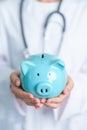 Doctor holding piggy bank and putting coin. and Healthcare cost, Money Saving, Health Insurance, Medical, Donation and Financial Royalty Free Stock Photo