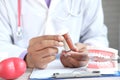 doctor holding pill container and plastic dental teeth model on table Royalty Free Stock Photo