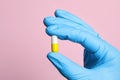 Doctor holding pill on pink background, closeup. Space for text Royalty Free Stock Photo