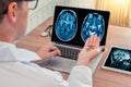 Doctor holding pills for disease with x-ray of brain and skull on the laptop. Digital tablet on the wooden desk