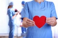 Doctor holding red heart at hospital, closeup