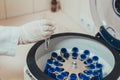 Doctor holding a sample and a medical centrifuge at the blurred background in a laboratory.