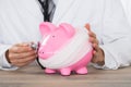 Doctor Holding Stethoscope To Pink Piggy Bank With Bandage Royalty Free Stock Photo