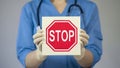 Doctor holding stop sign, warning about unhealthy lifestyle, harmful habits