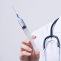 Doctor holding syringe with face mask, concept of young female physican injects coronavirus, COVID-19 vaccine on white background