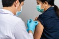 Doctor holding syringe and using cotton before make injection to woman in medical mask. Covid-19 or coronavirus vaccine Royalty Free Stock Photo